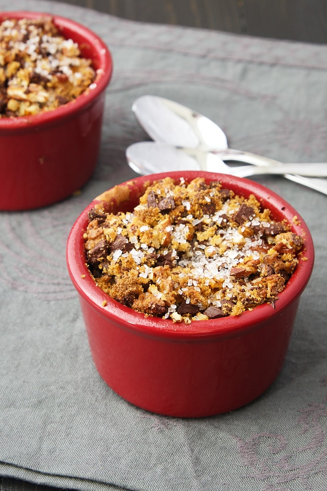 Dark Chocolate Bourbon Bread Puddings in red ramekins on a patterned gray fabric