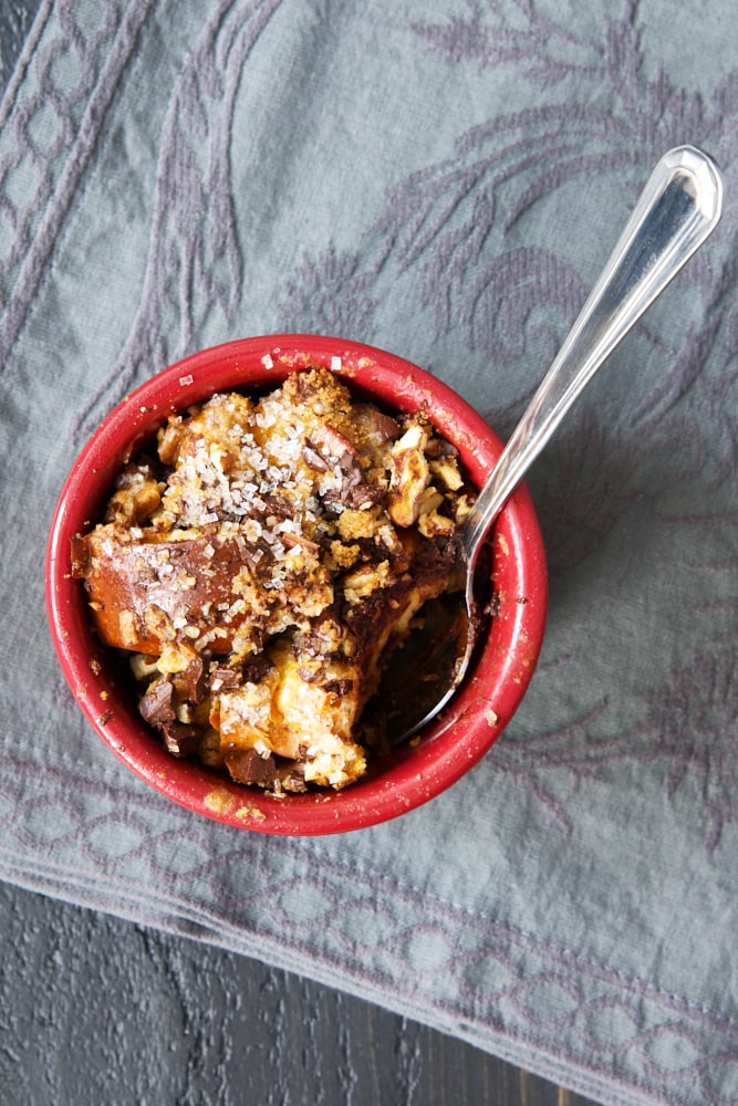 overhead view of Dark Chocolate Bourbon Bread Pudding in a red ramekin on a gray fabric