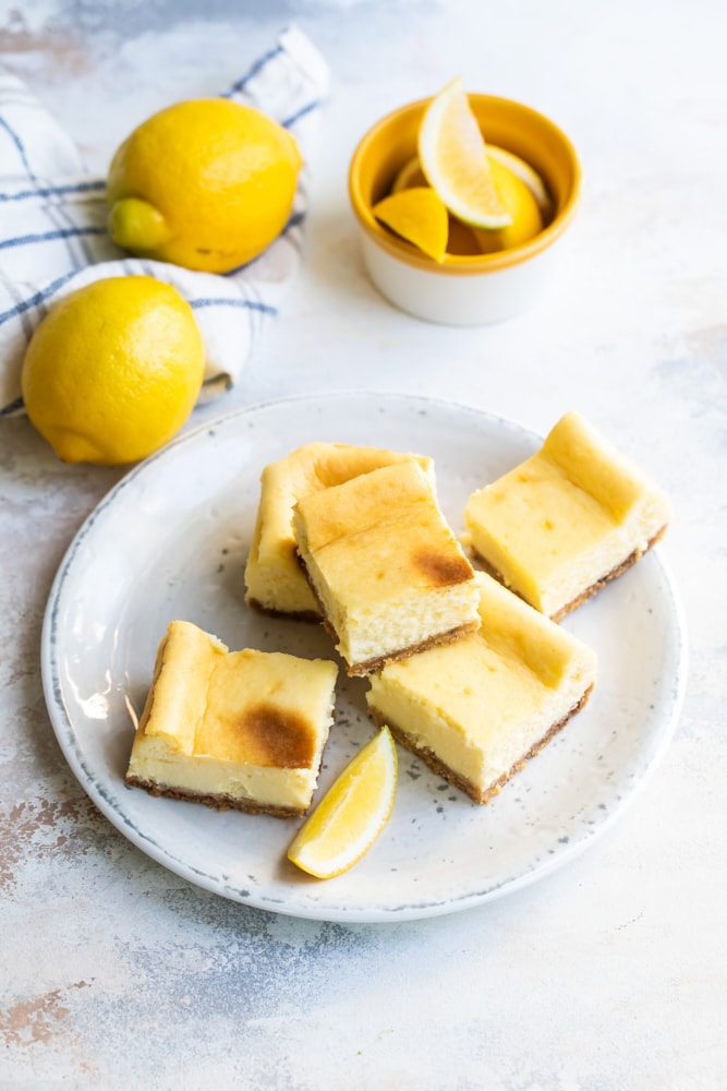 Limoncello Cheesecake Squares stacked on plate with lemon garnish