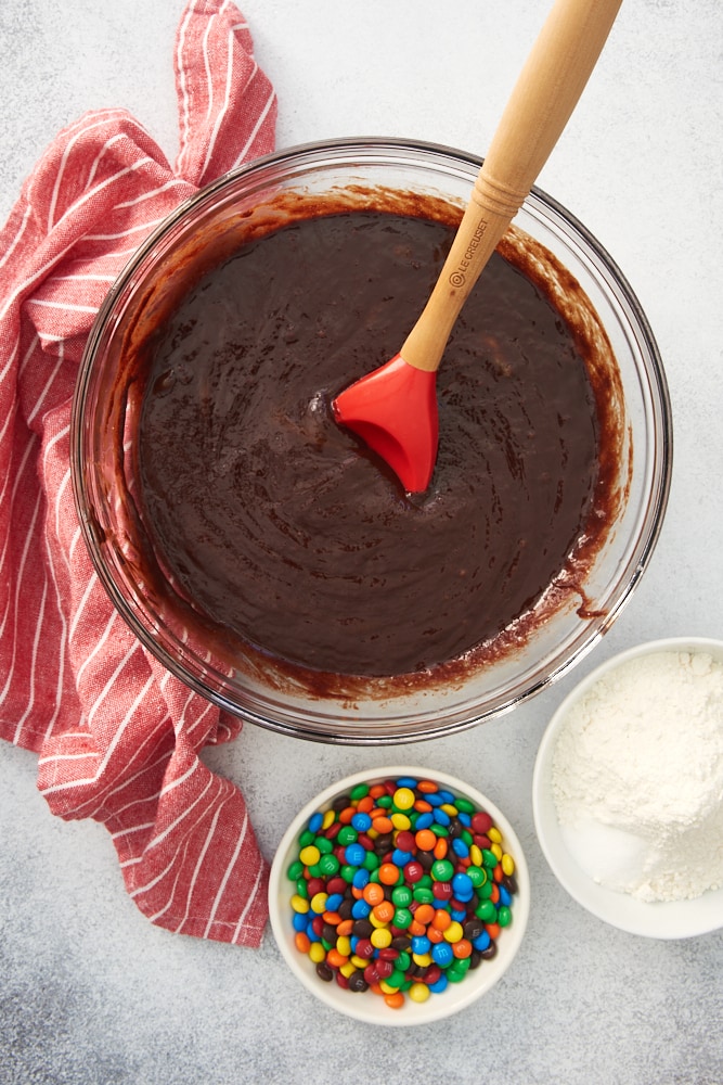overhead view of partially mixed brownie batter in a glass bowl