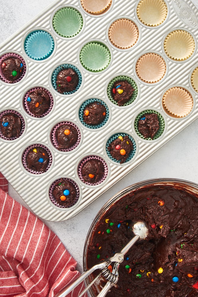 overhead view of M&M Brownie Bites batter scooped into lined mini muffin pans