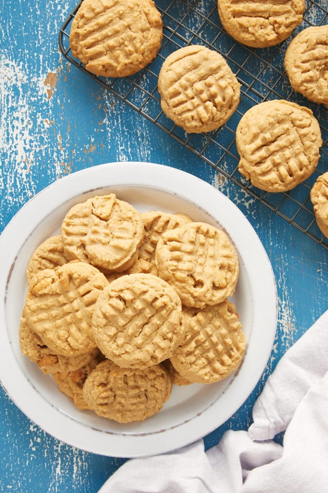 overhead view of Peanut Butter Cookies on a white plate and on a wire cooling rack