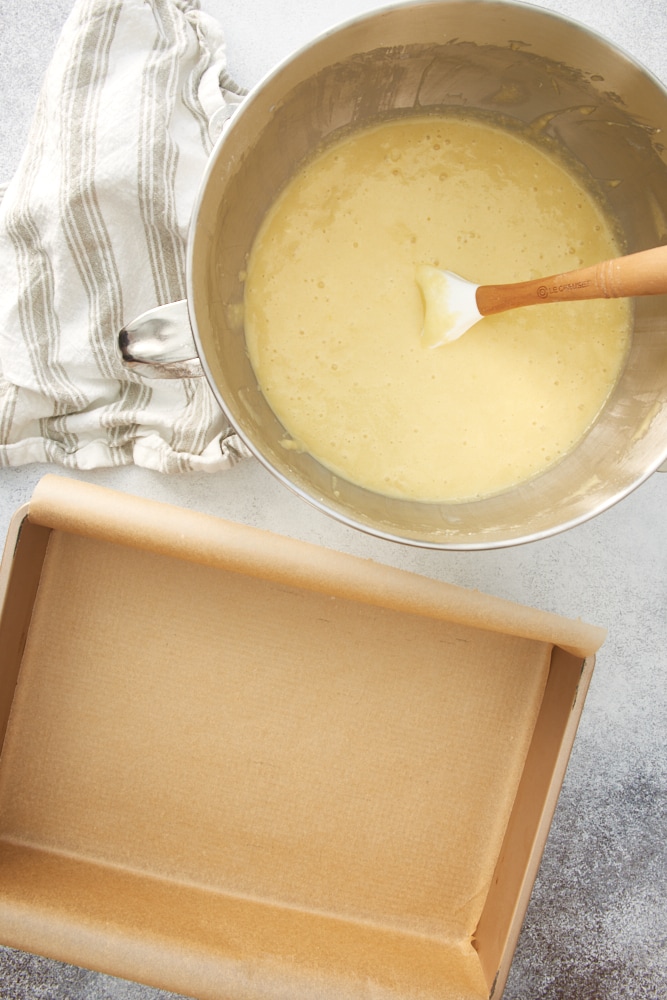 Overhead view of cake batter in mixing bowl and prepared baking pan