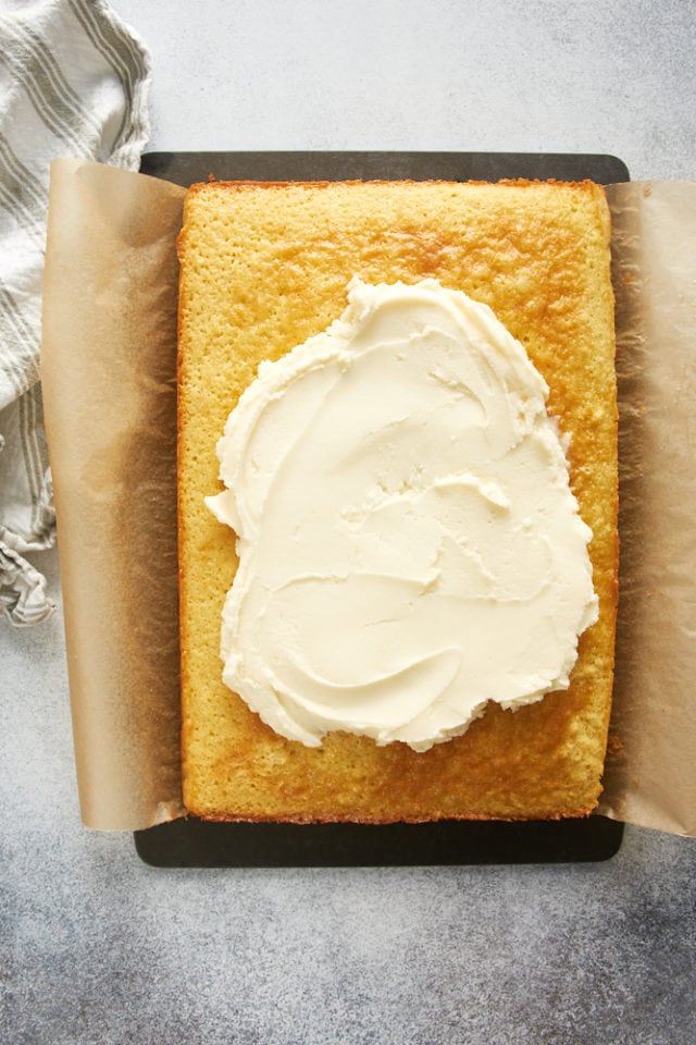 Overhead view of frosting being spread onto vanilla cake in pan