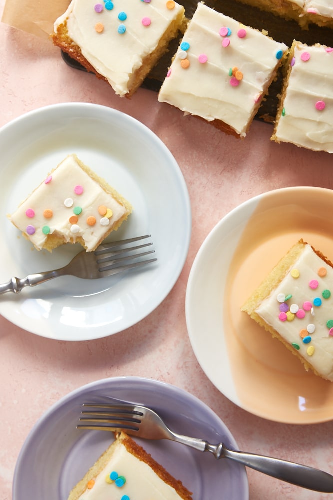 Overhead view of slices of Vanilla Cake with Vanilla Frosting on colorful plates