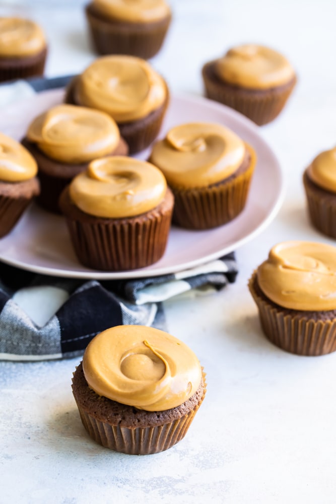 Mexican chocolate cupcakes with plate of cupcakes on cloth napkin in background