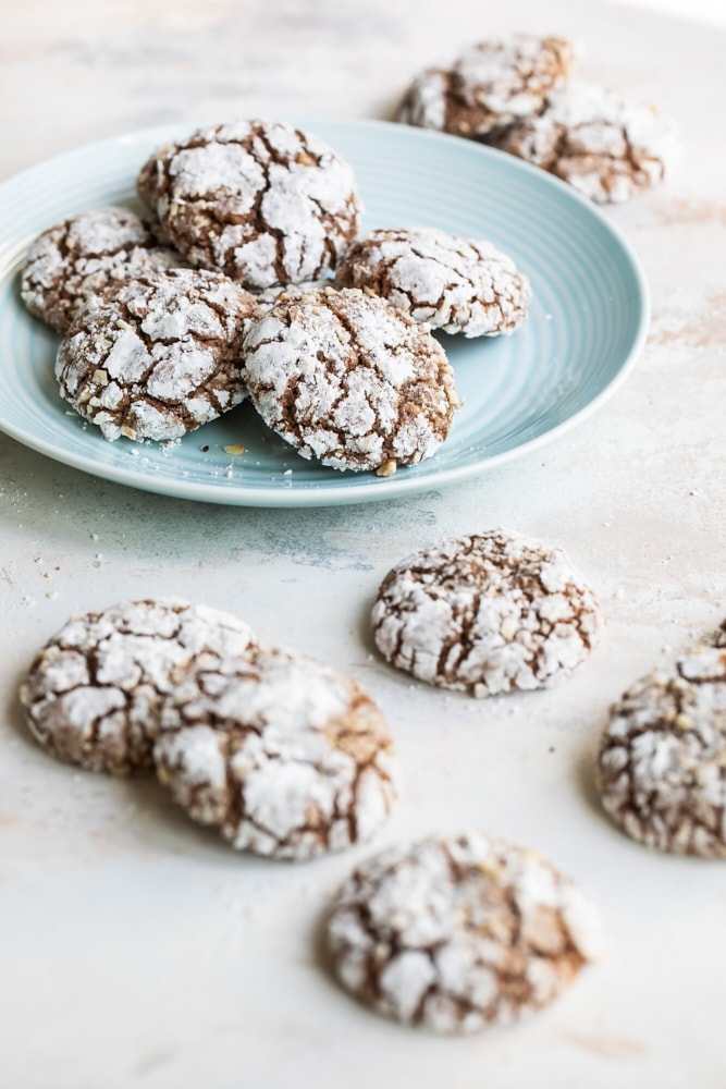 Hazelnut crinkle cookies on a light blue plate with more cookies around the plate.