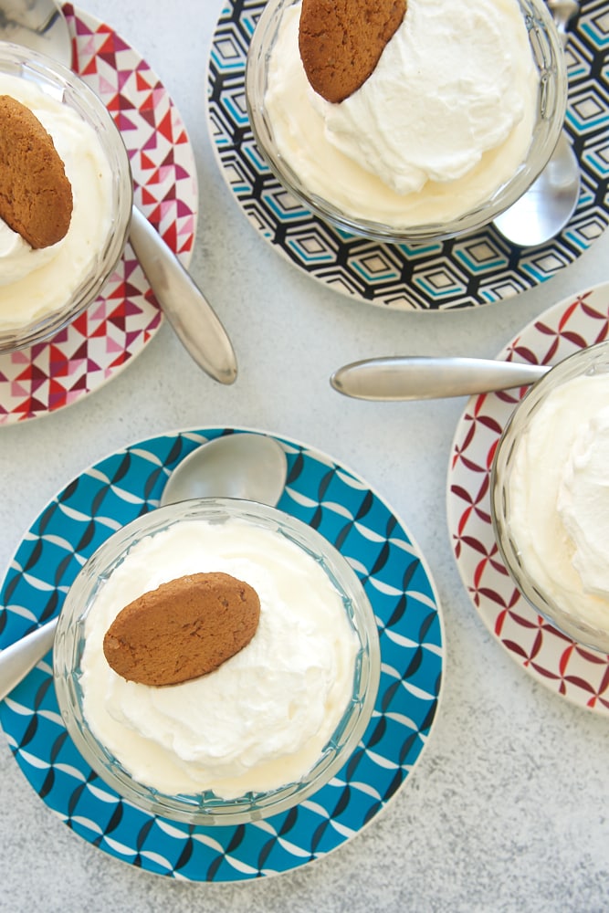 overhead view of No-Bake Lemon Cheesecakes in glass serving bowls on multi-colored plates