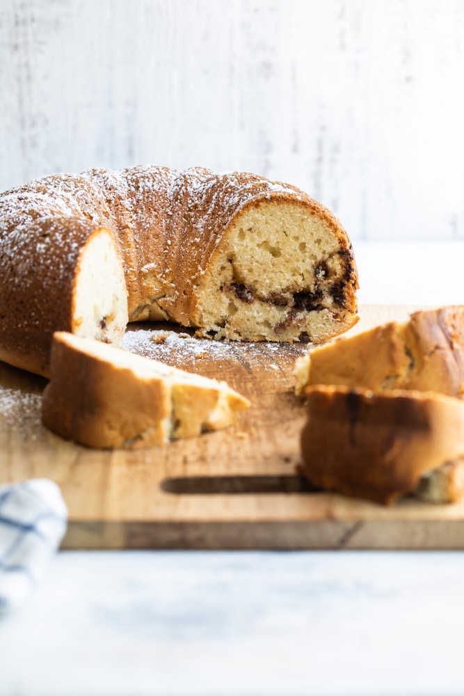 Half of a Nutella bundt cake on cutting board with pieces of cake in foreground