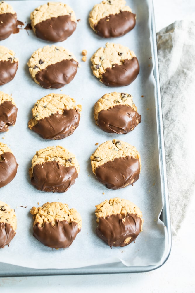 Chocolate-dipped peanut butter meltaways on a parchment-lined baking sheet.