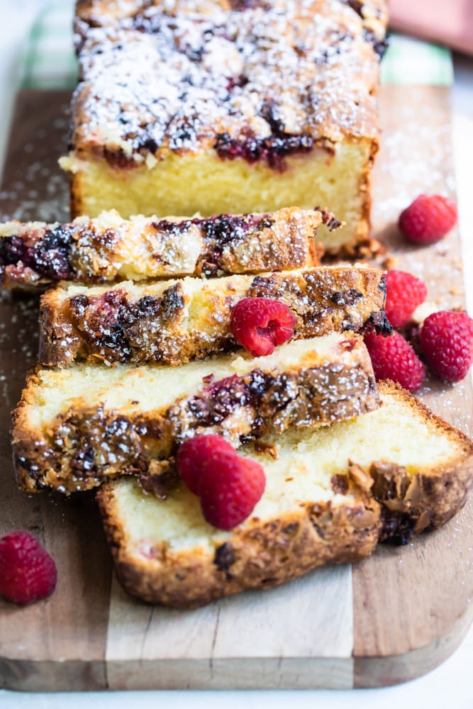 Sliced raspberry white chocolate almond bread on a wooden cutting board.