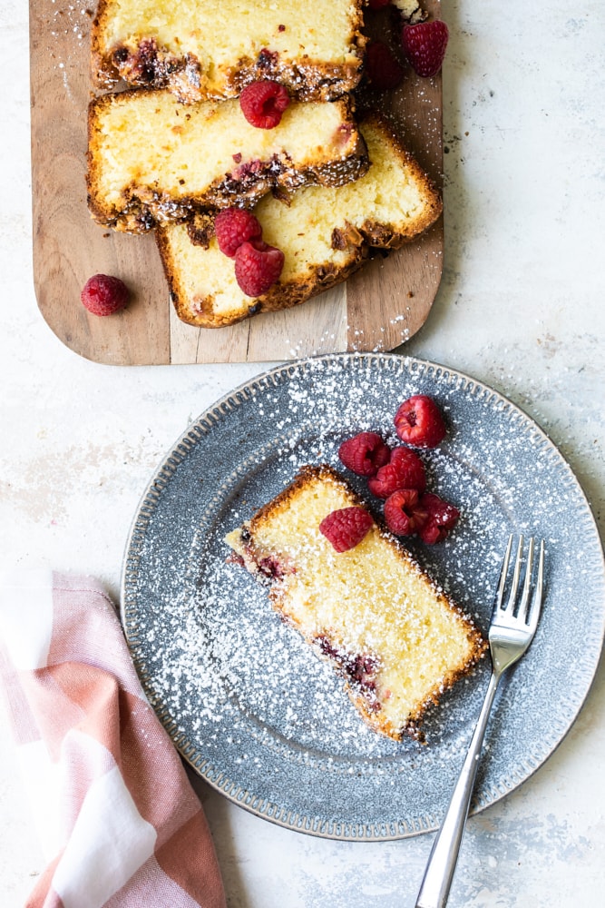 Overhead view of almond loaf slice on blue plate with fork