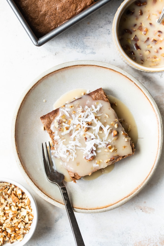 Overhead view of German chocolate cake topped with sauce on a beige plate.