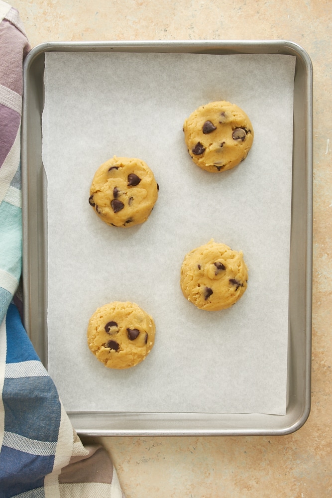 overhead view of chocolate chip cookie dough on a parchment-lined baking sheet
