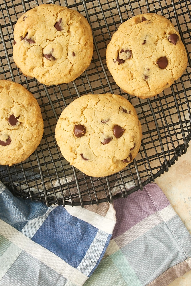 Overhead view of four chocolate chip cookies on a round wire rack.