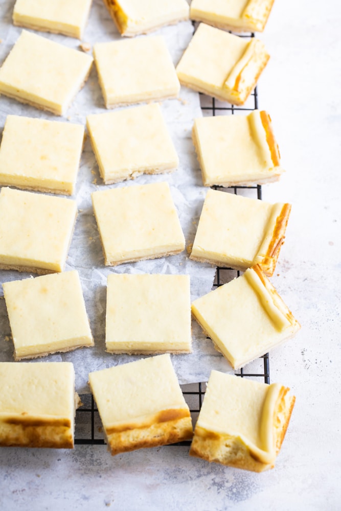 Overhead view of cheesecake bars on a parchment-lined wire rack.