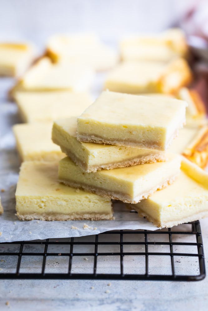 Vanilla cheesecake bars stacked on wire rack