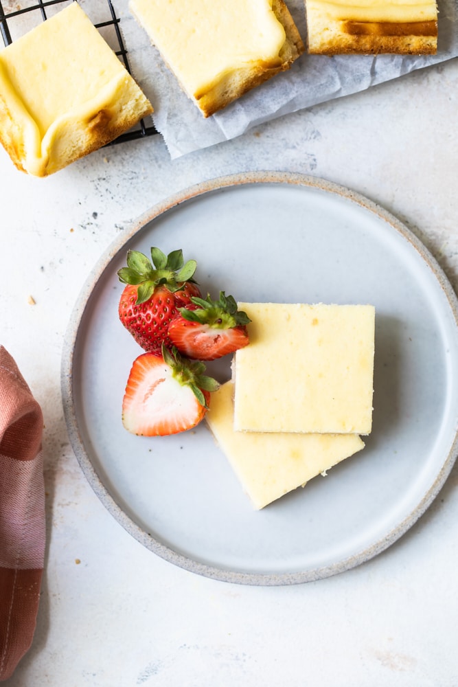 Overhead view of vanilla bean cheesecake bars served with fresh strawberries.