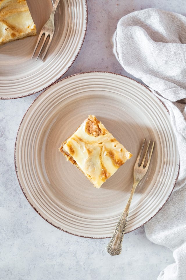 overhead view of a slice of butterscotch cream cheese bars on a beige plate