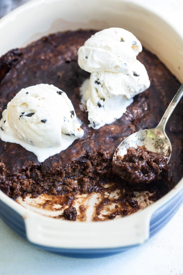 ice cream-topped Brownie Pudding Cake in a blue oval baking dish