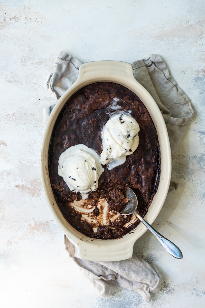Overhead view of Brownie Chocolate Pudding Cake in baking dish with scoops of ice cream