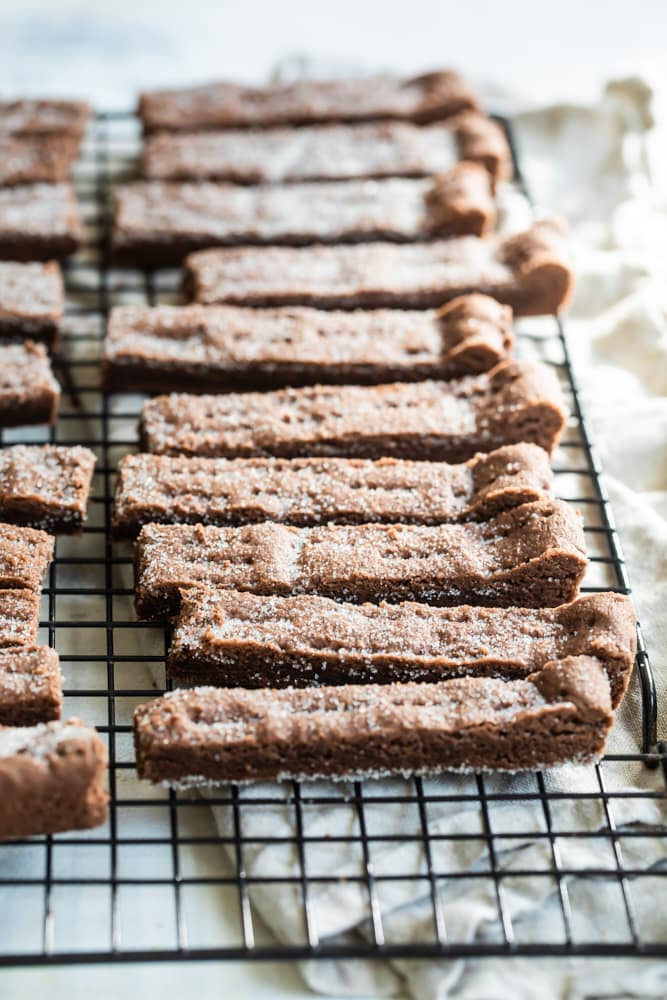 Chocolate shortbread cookies lined up on a wire rack.