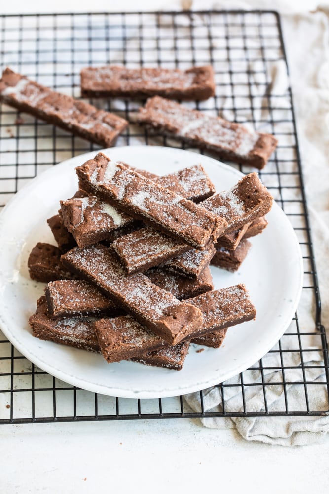 Chocolate shortbread on a white plate on a wire rack.