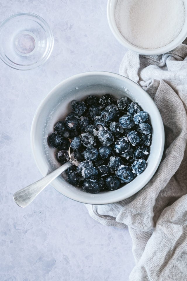 Sweetened blueberries mixed with lemon juice in a white bowl.