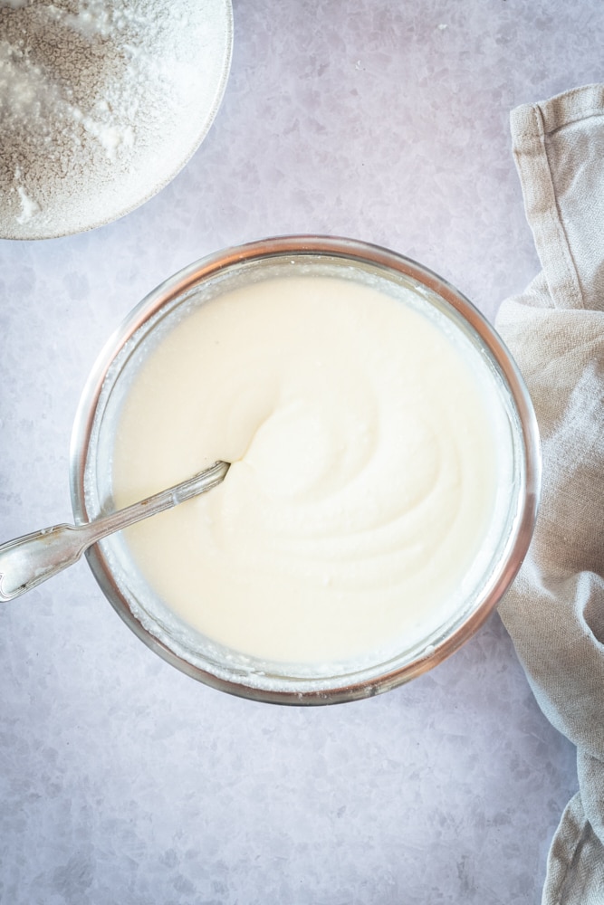 Overhead view of cream cheese filling in glass mixing bowl