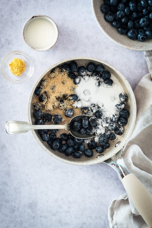 Overhead view of blueberries and sugar in pan