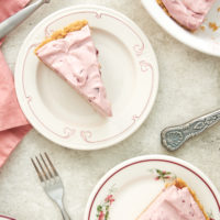 overhead view of slices of No-Bake Cherry Cheesecake Pie on red-rimmed white plates