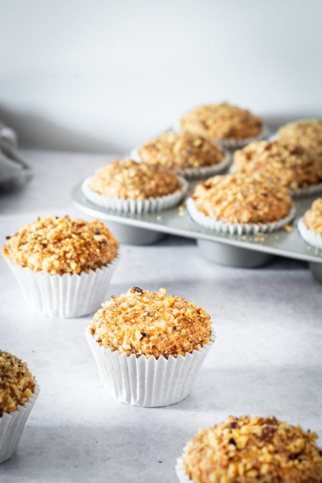 Sour Cream Coffee Cake Muffins on a gray surface and in a muffin pan