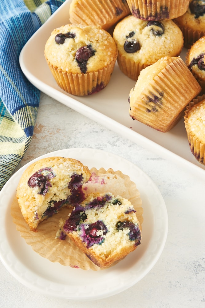 A blueberry muffin split in half on a white plate.