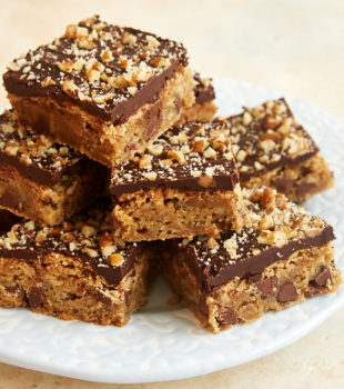 Chocolate Chip Ganache Blondies piled on a light blue and white plate