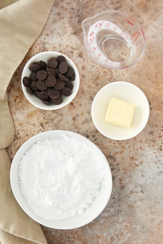 ingredients for chocolate glaze, including chocolate, butter, and confectioners' sugar