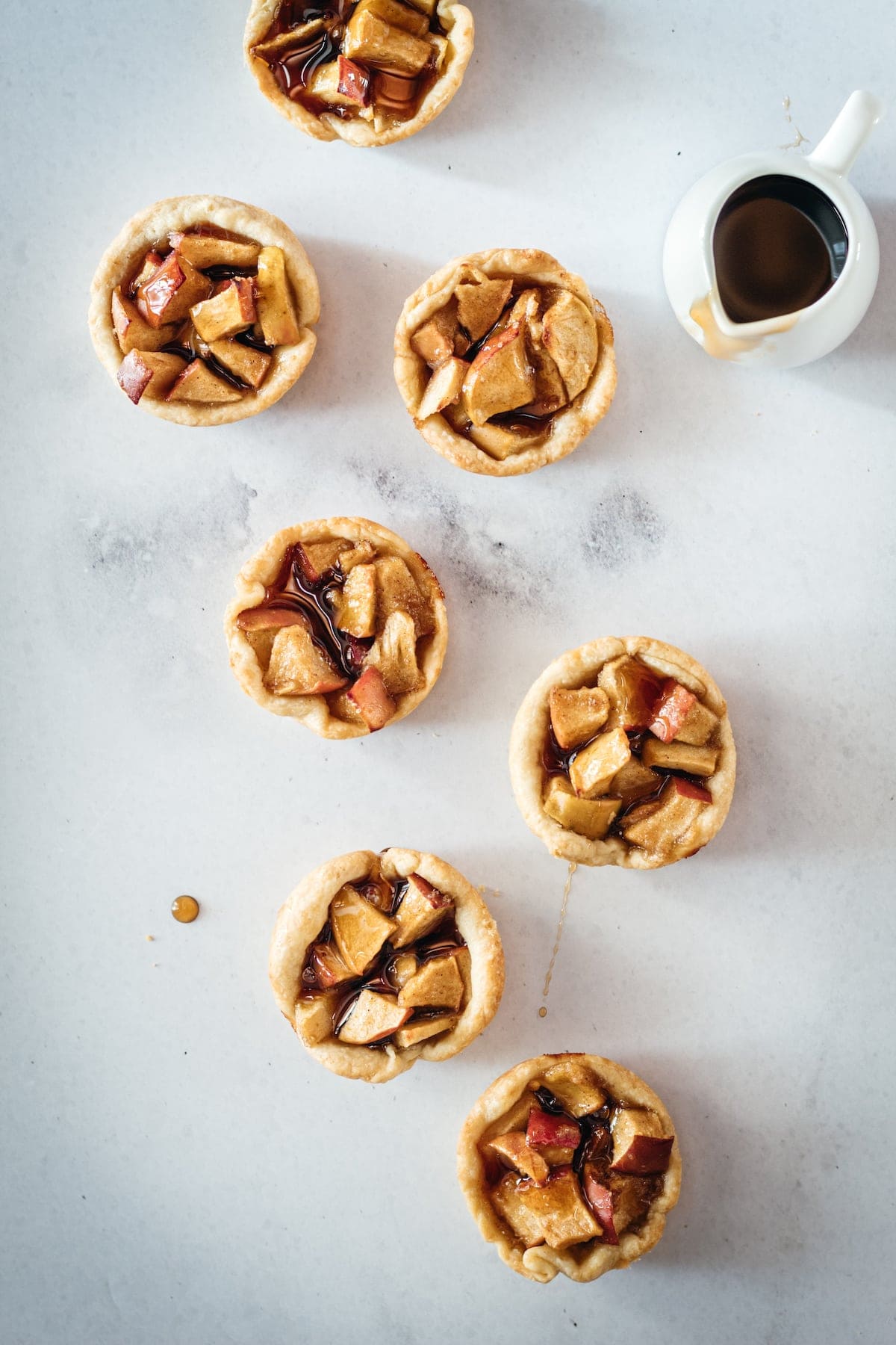 Overhead shot of Mini Caramel Apple Pies on marble slab