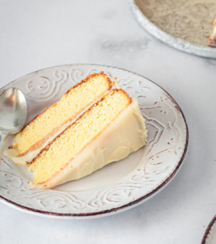 Slice of Caramel Cake with Caramel Cream Cheese Frosting on plate with spoon