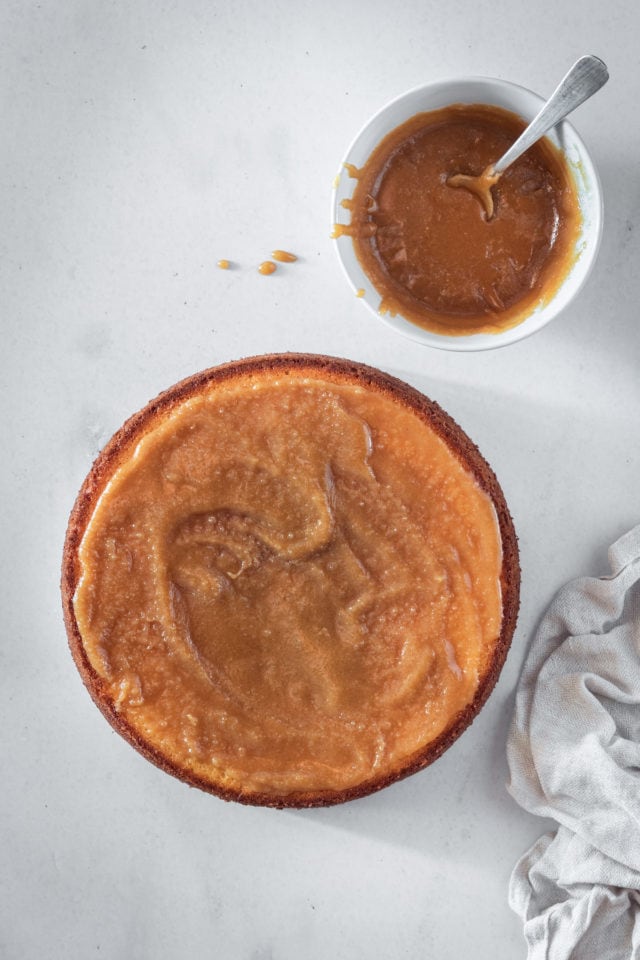 Overhead shot of caramel spread onto a layer of cake.