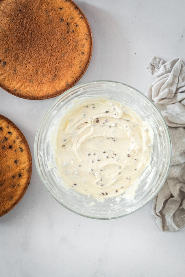 Overhead shot of Chocolate Chip Buttercream in glass bowl and baked cake layers