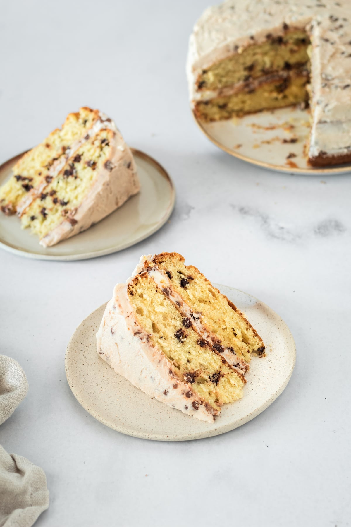 Slice of Chocolate Chip Cake on plate with another piece in background