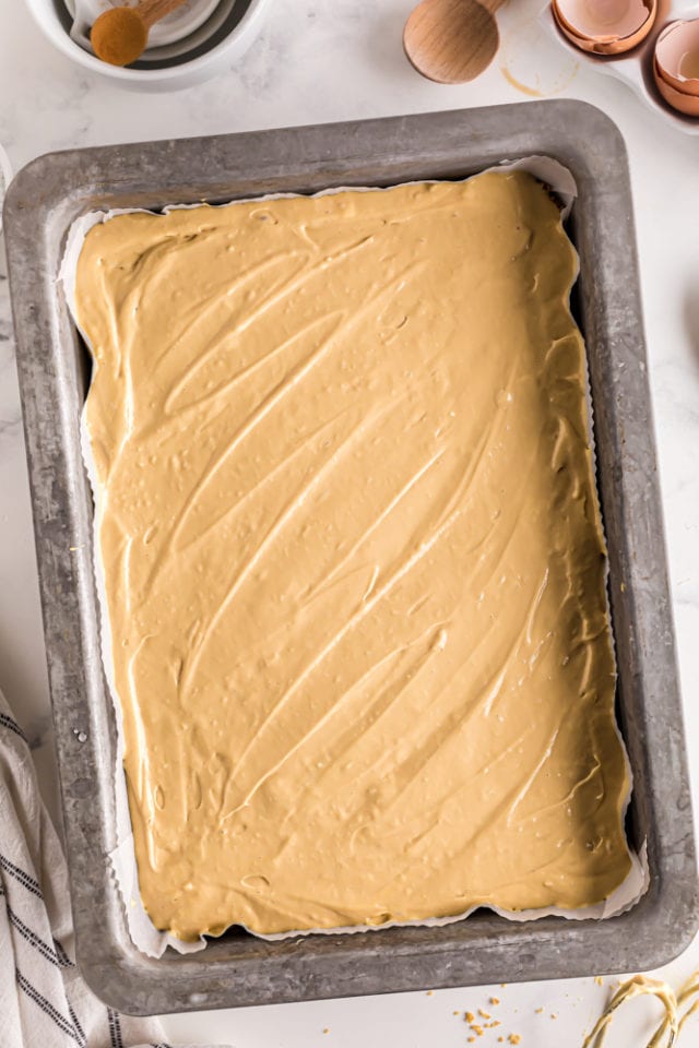 overhead view of dulce de leche cheesecake filling spread in a 9x13 baking pan