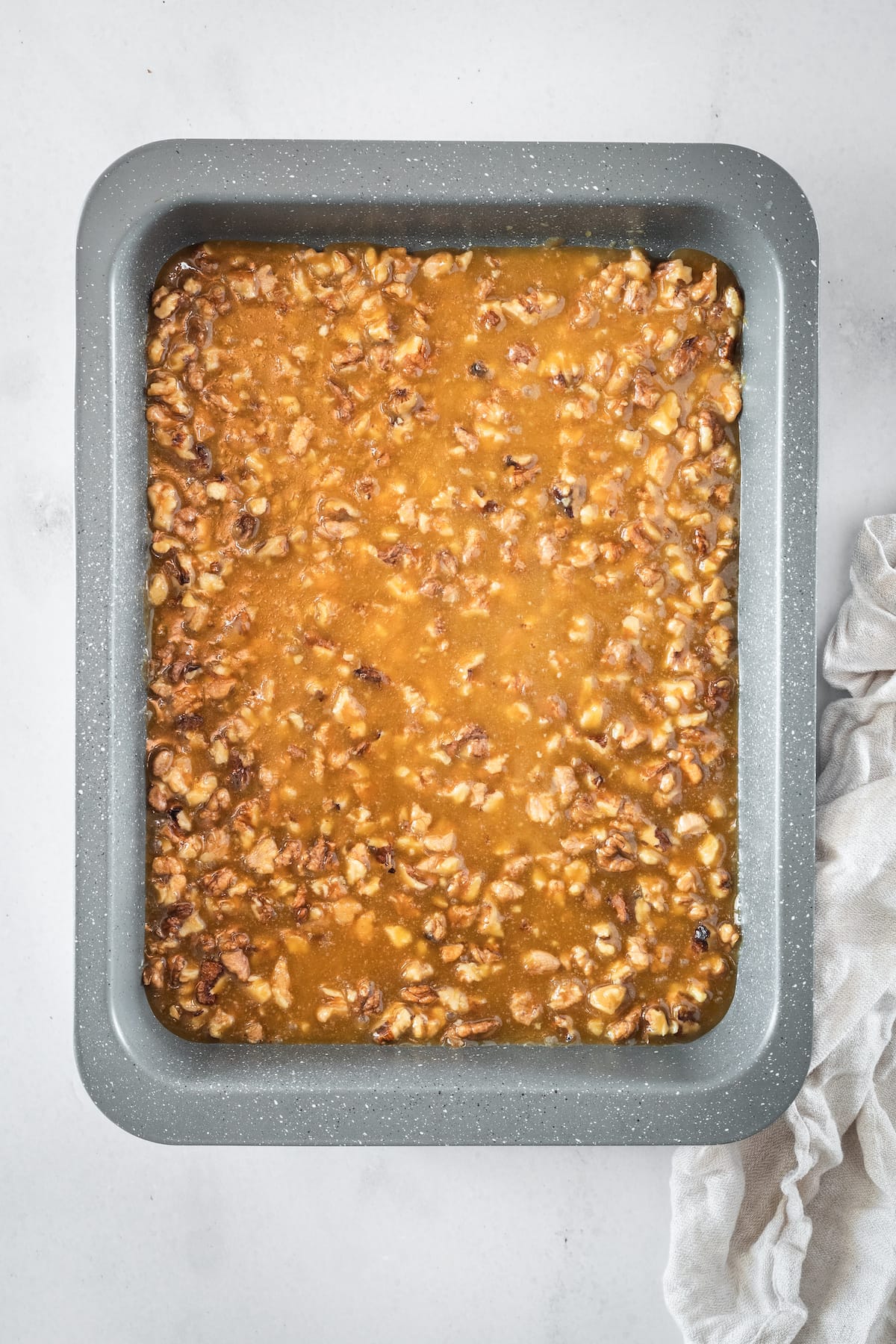 Overhead shot of rich caramel pecan sauce poured into a metal baking pan