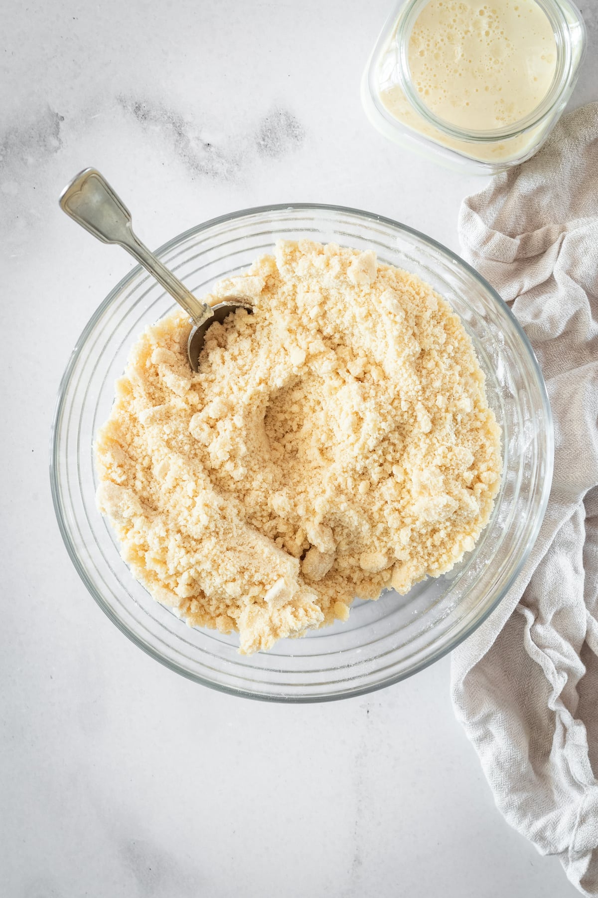 Overhead shot of biscuit dough in a glass bowl after butter has been cut in, before adding buttermilk