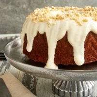 Cinnamon Hazelnut Bundt Cake topped with a brown butter glaze and displayed on a pewter cake stand