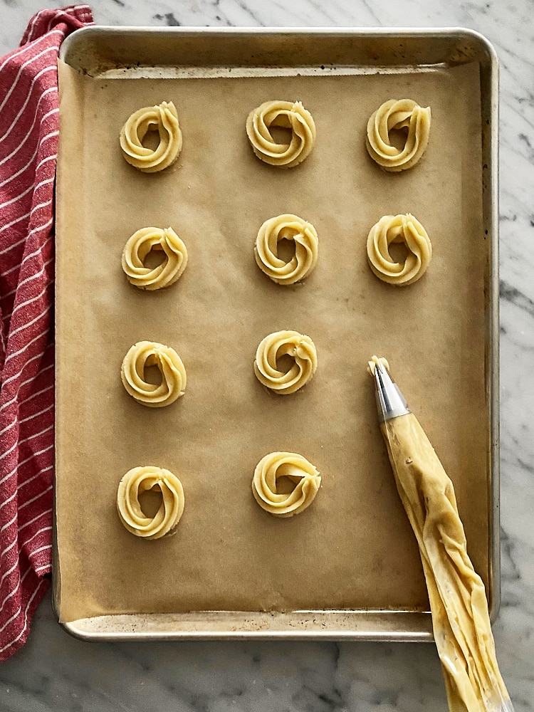 Danish Butter Cookie dough piped onto a parchment-lined baking sheet