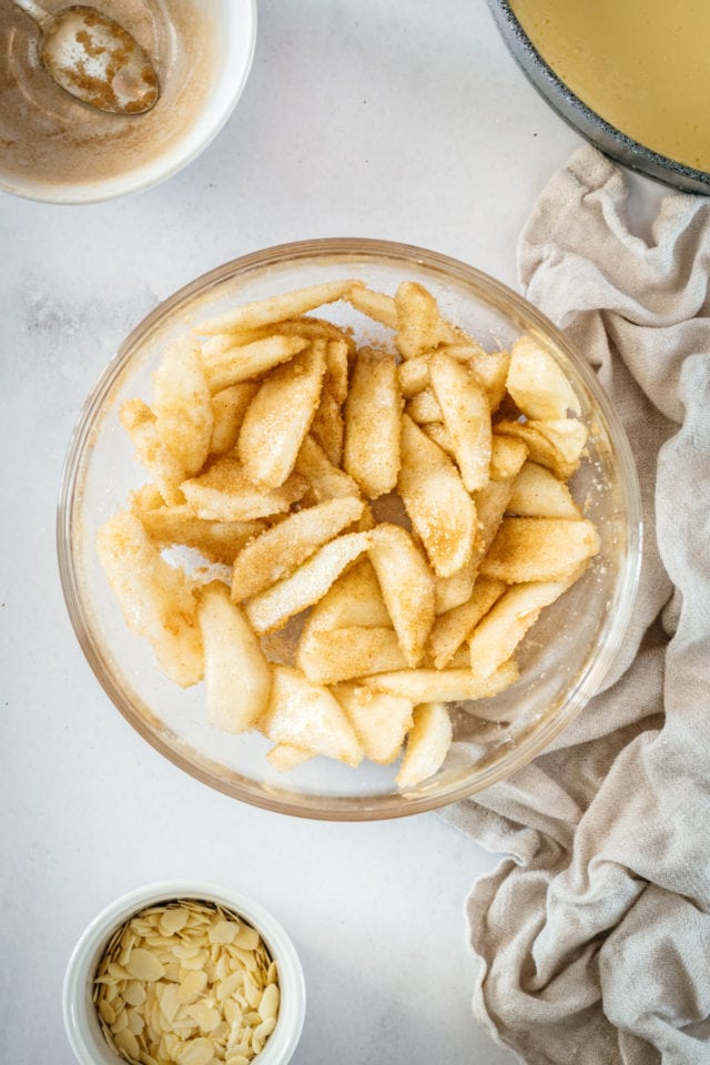 Overhead shot of pear slices in glass bowl after tossing with cinnamon sugar