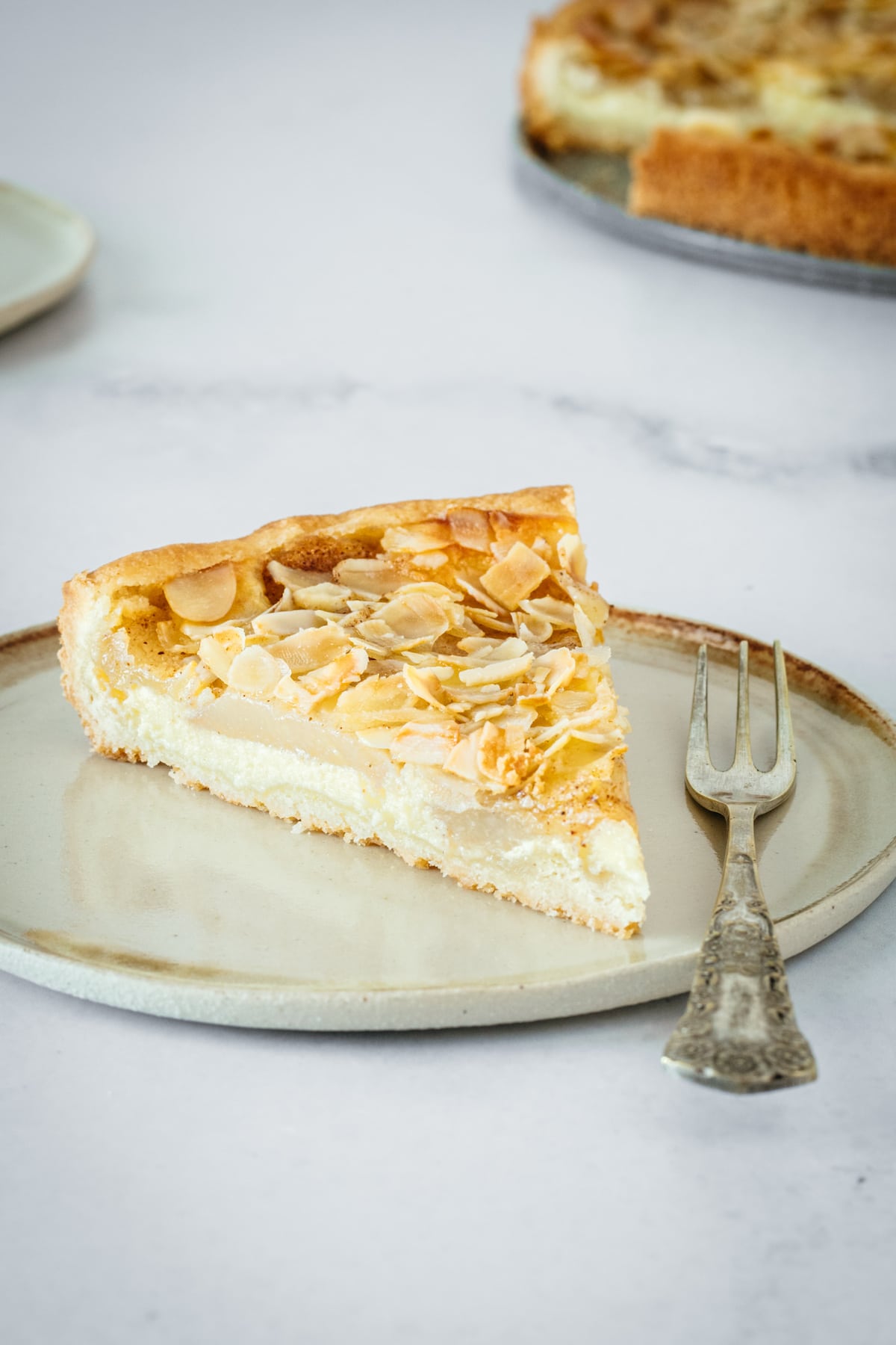 Closeup of Almond Pear Cream Cheese Tart slice on plate with fork