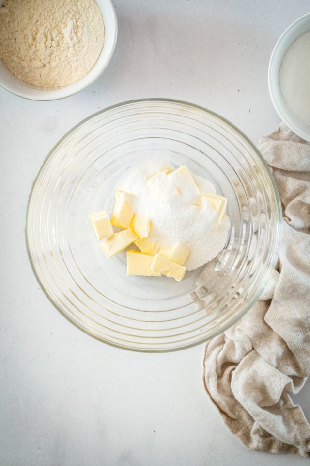 Overhead view of butter and sugar in glass mixing bowl