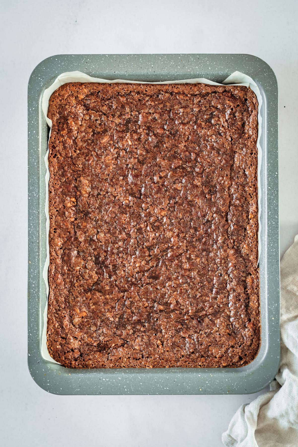 Overhead view of chocolate pecan pie bars in parchment lined baking pan