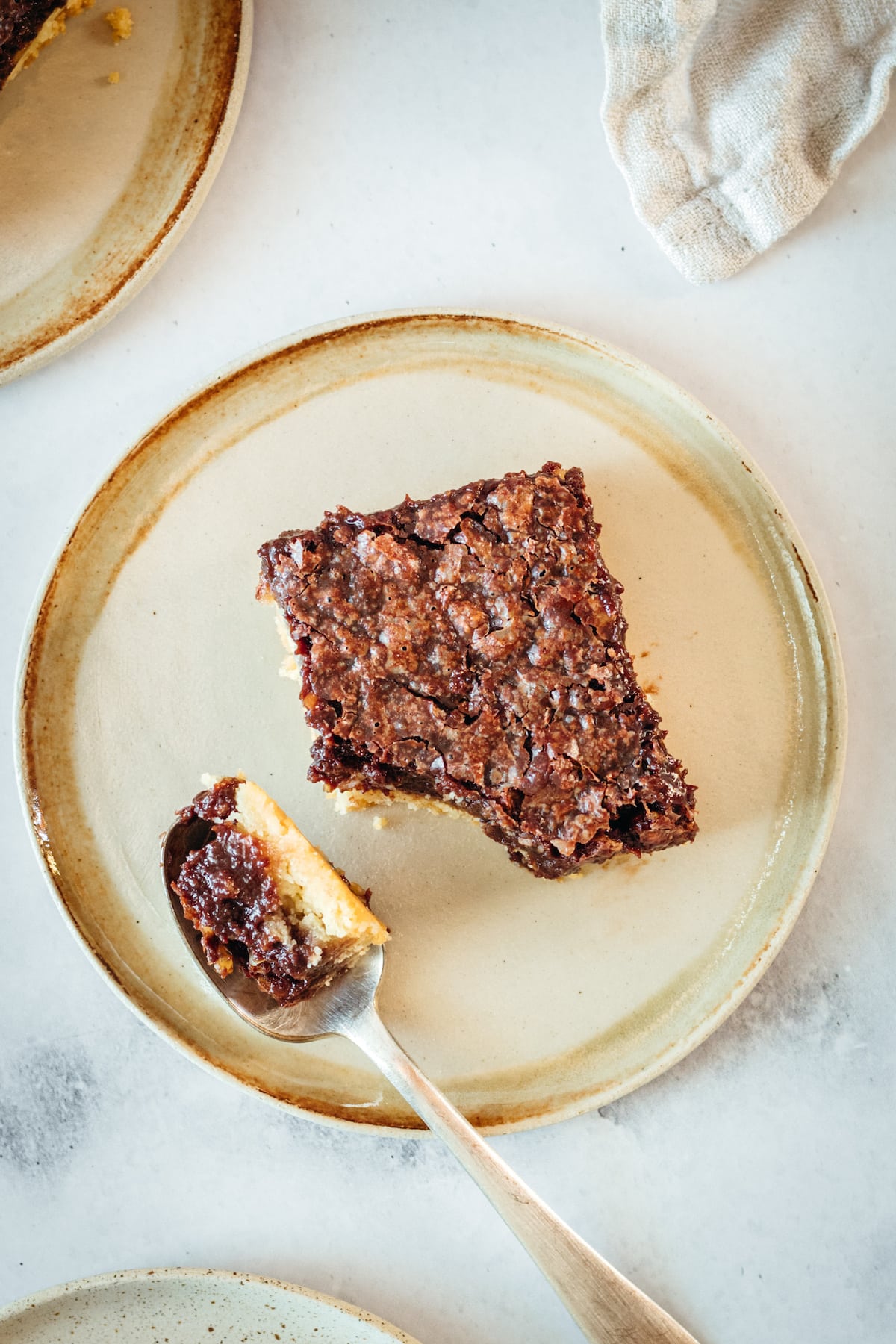 Overhead view of a plated pecan pie bar with a bite on a spoon